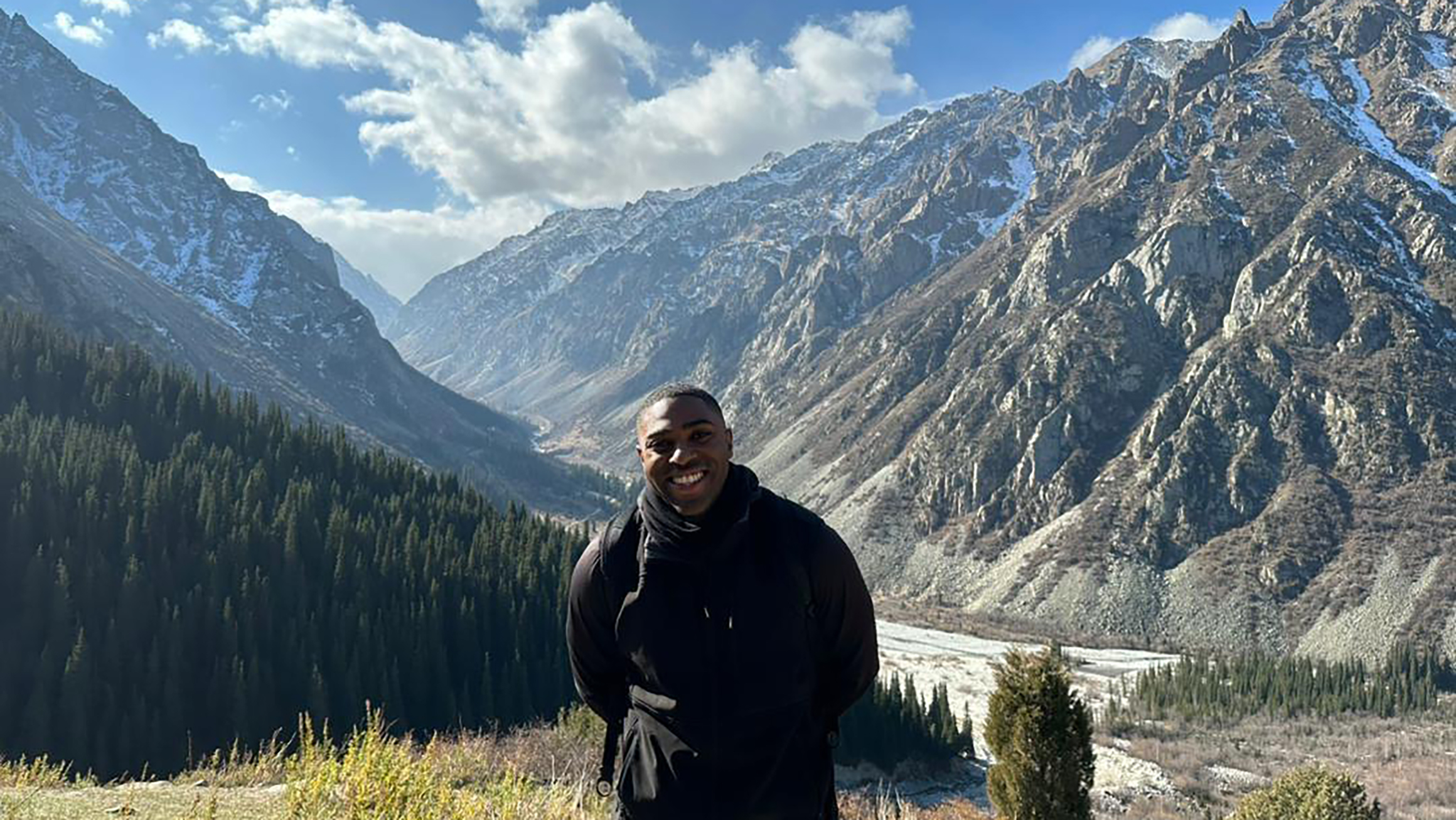 A man stands in front of mountains.