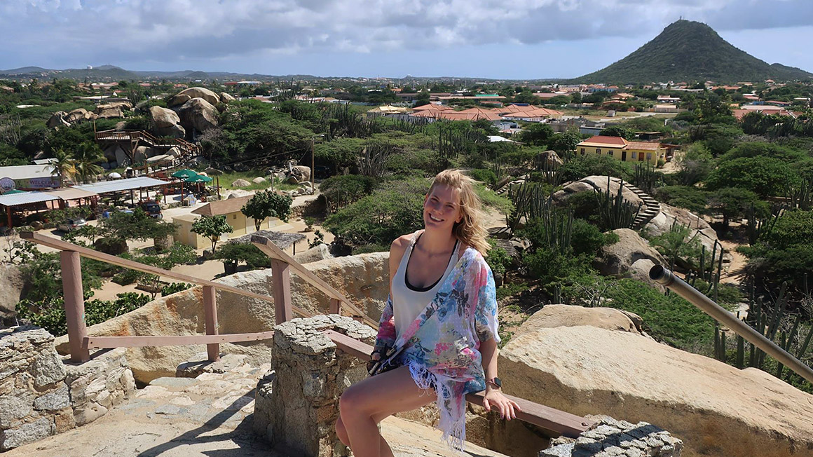 Barbara Van sitting on rocks overlooking a landscape.