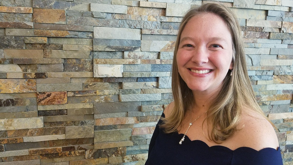 Jennifer Tomak is pictured in front of a stone wall.