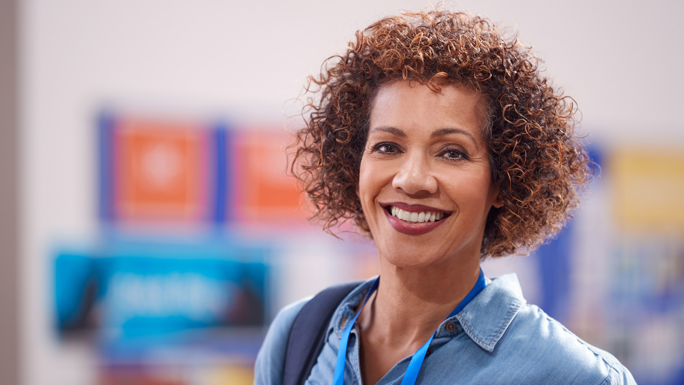 A woman is standing with a strap of a workbag over her left shoulder.