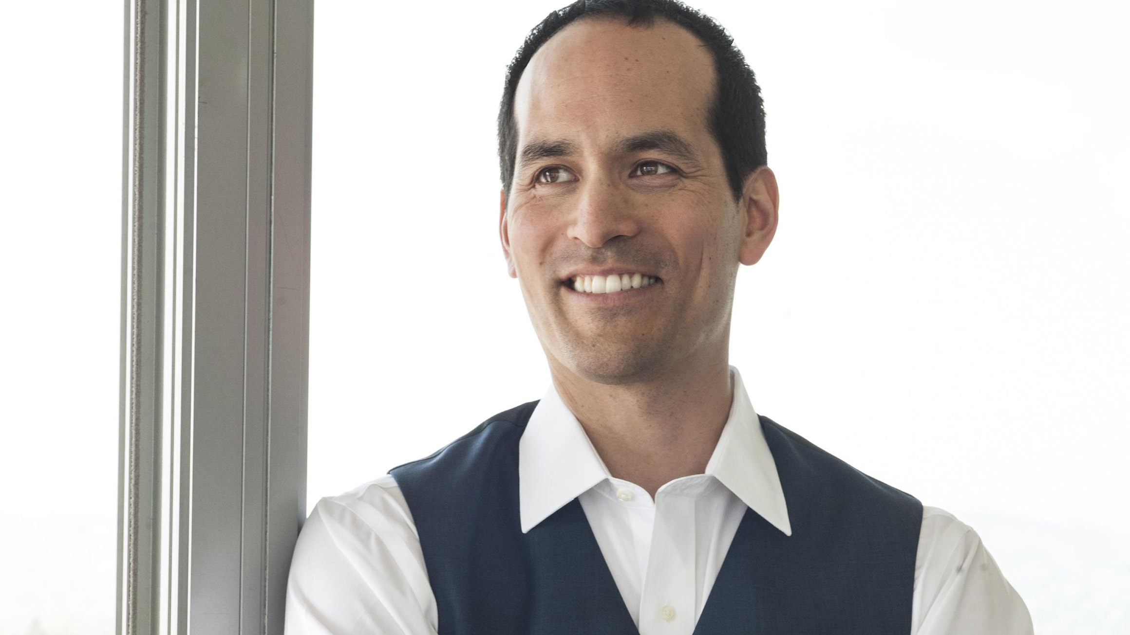 Ian Truitner poses in front of a floor-to-ceiling glass window