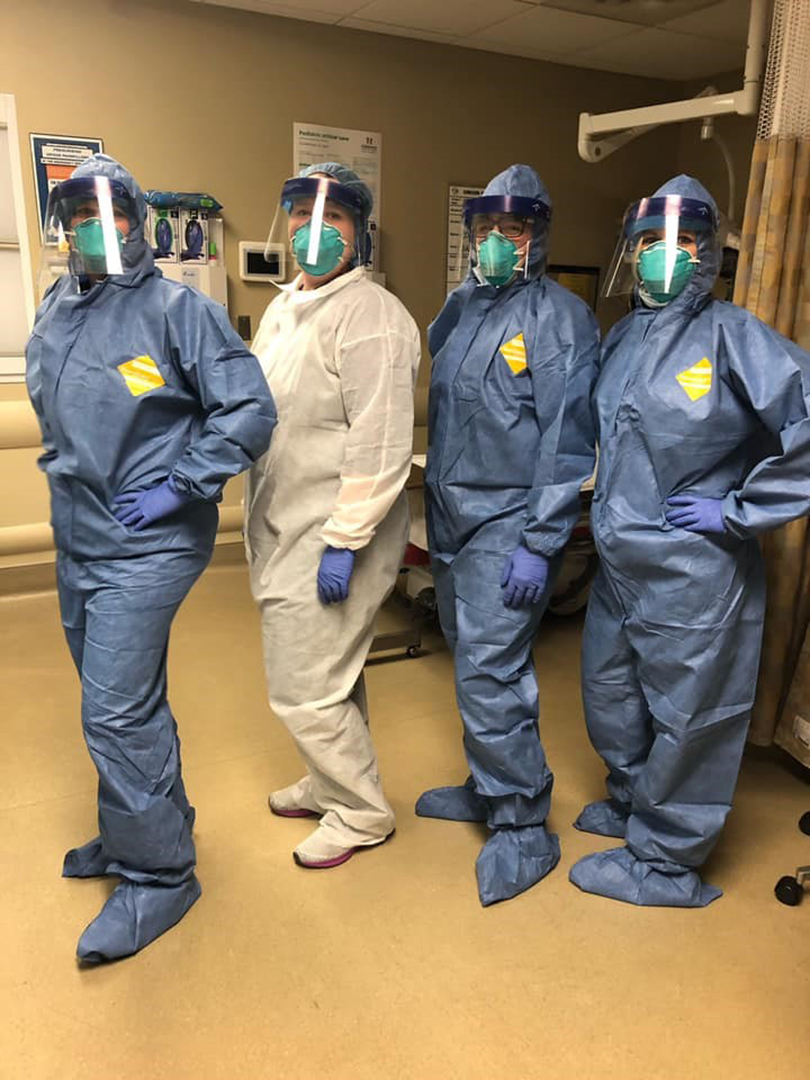 Four nurses wearing protective gear pose.