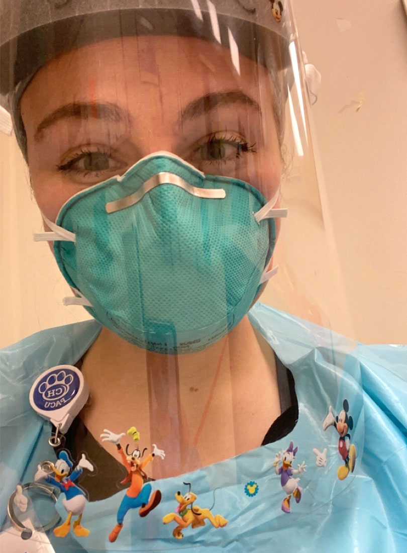 Jennie Kriznik is wearing a mask and a face shield while working as a childlife specialist..