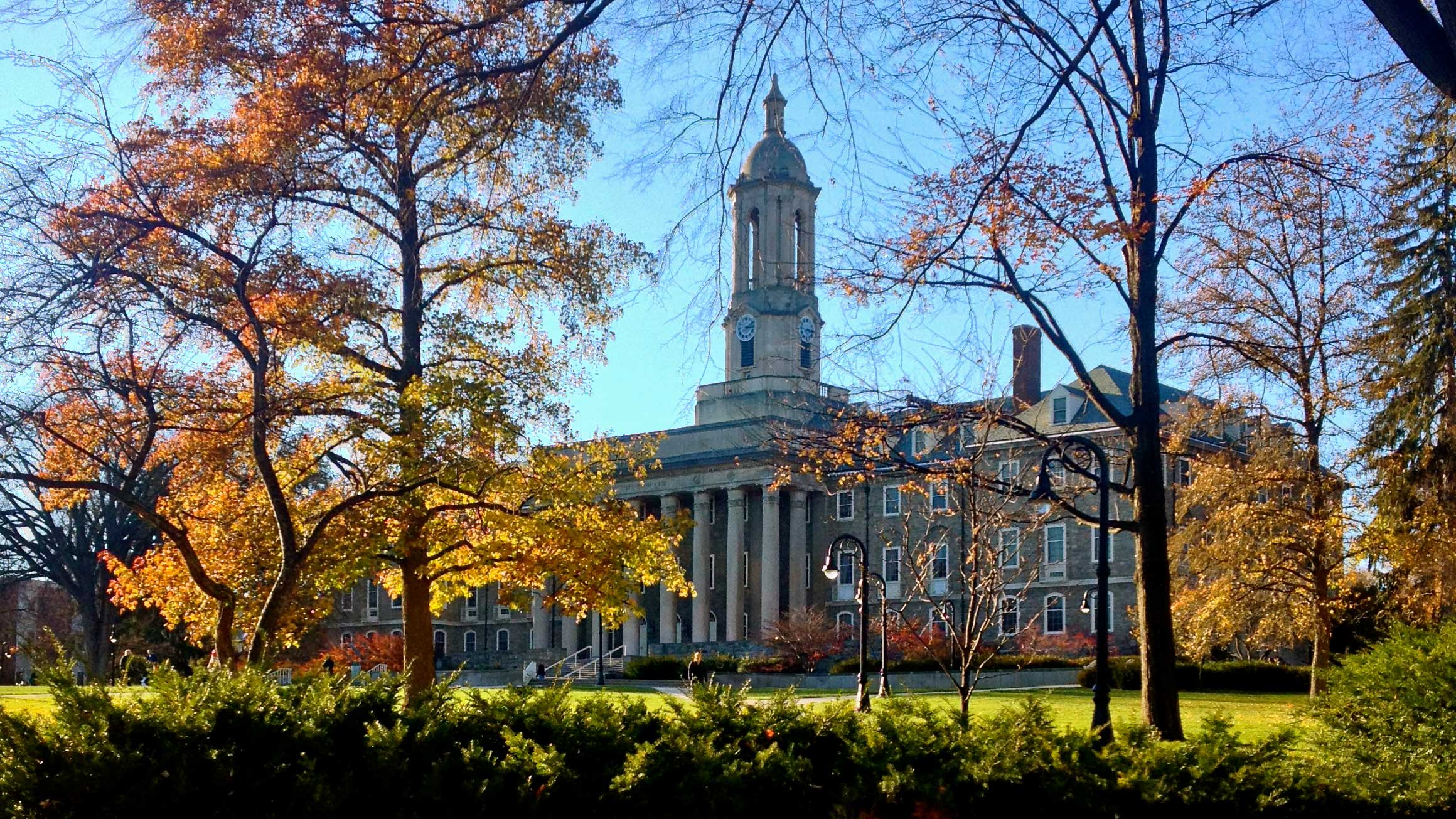 Old Main is pictured behind some trees.