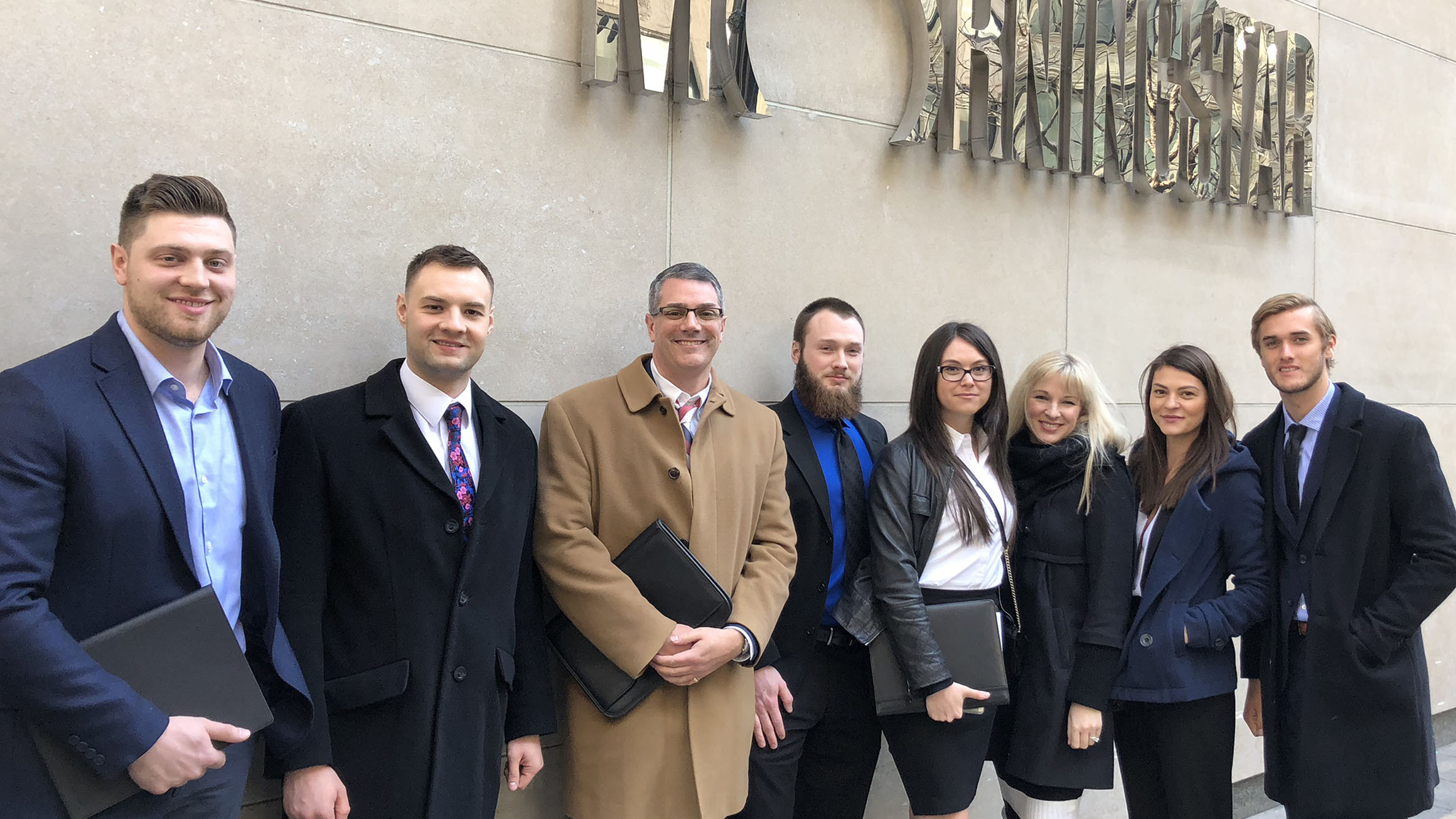 Eric Robbins stands with students on an educational trip outside a building