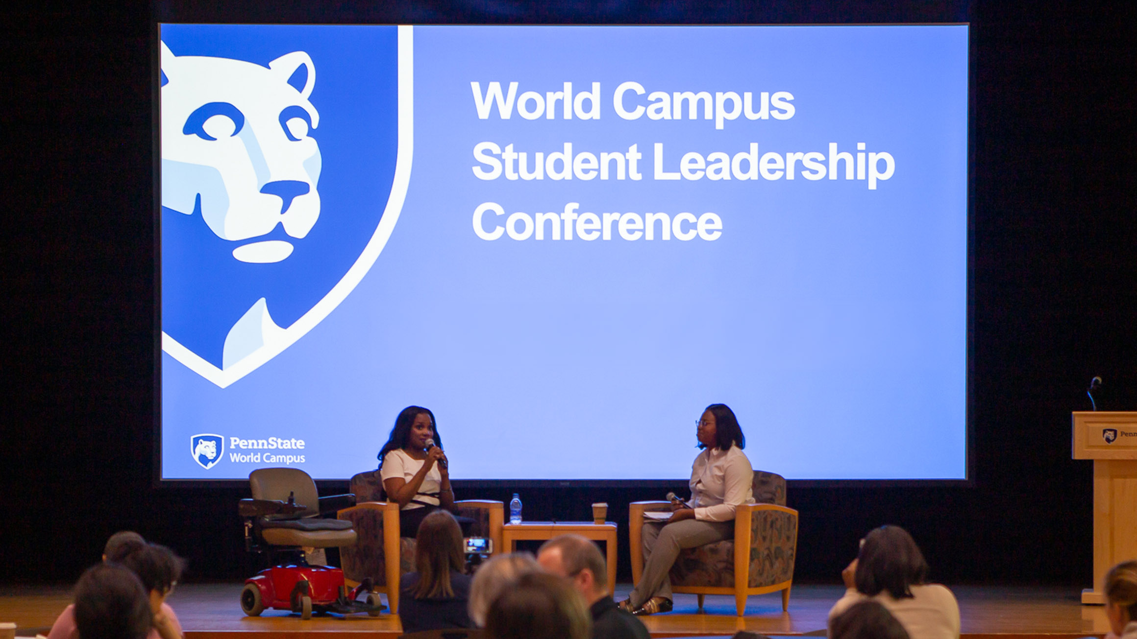 A conversation between Ola Ojawumi and Ashley Adams takes place on a stage.