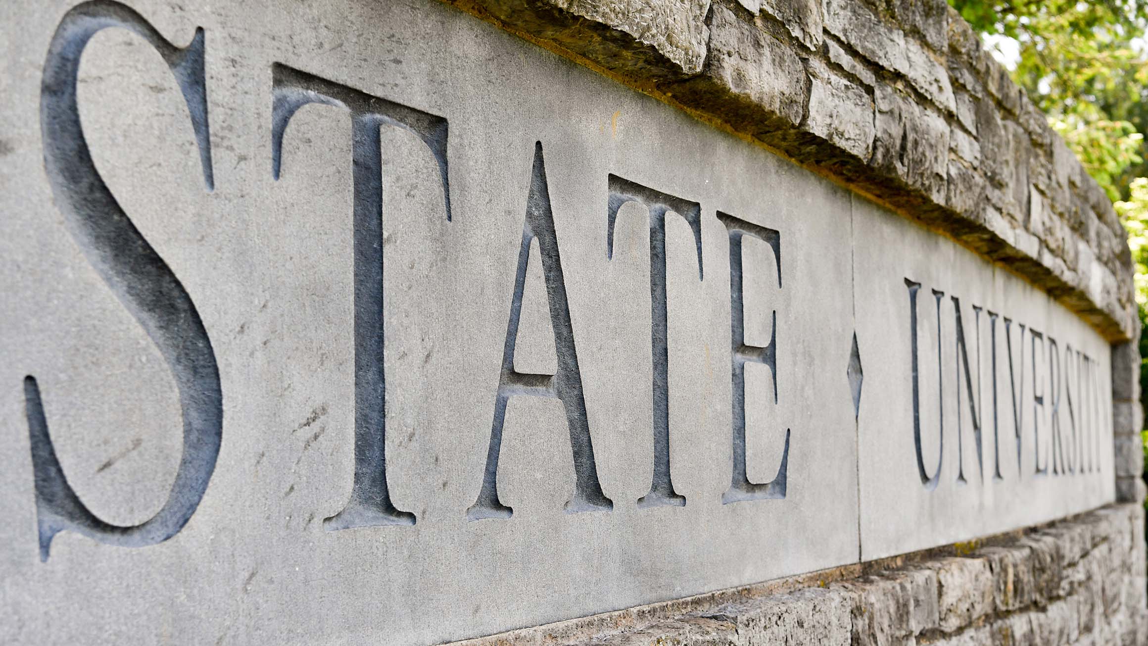 The words "State University" are shown on a stone wall