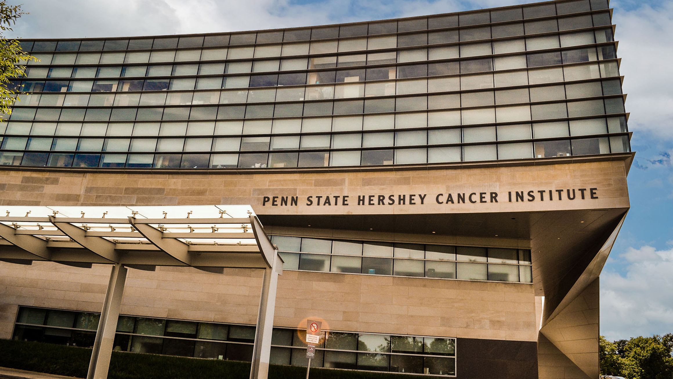 The photo shows a multi-story building with the words "Penn State Hershey Cancer Institute" written on it.