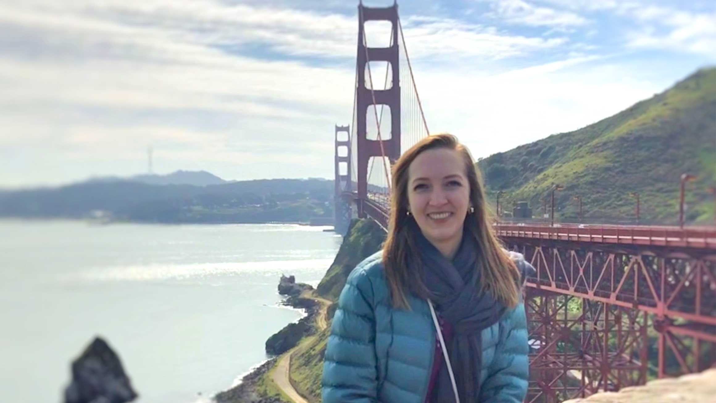 Michelle Hatch sits on a wall with the Golden Gate Bridge in the background