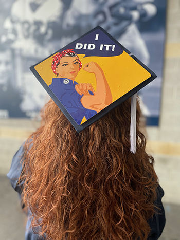 Rebecca Liebman is seeing with her graduation cap, which shows a picture of Rose the Riveter and the phrase "I did it"