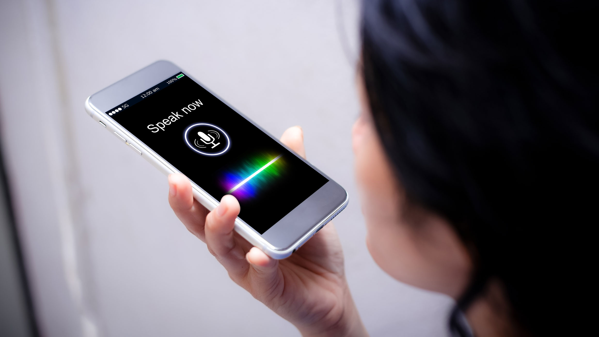 A woman speaks into her phone, which is translating her speech to text.