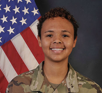 Mona Hill is seen wearing a camouflage uniform and a U.S. flag in the background