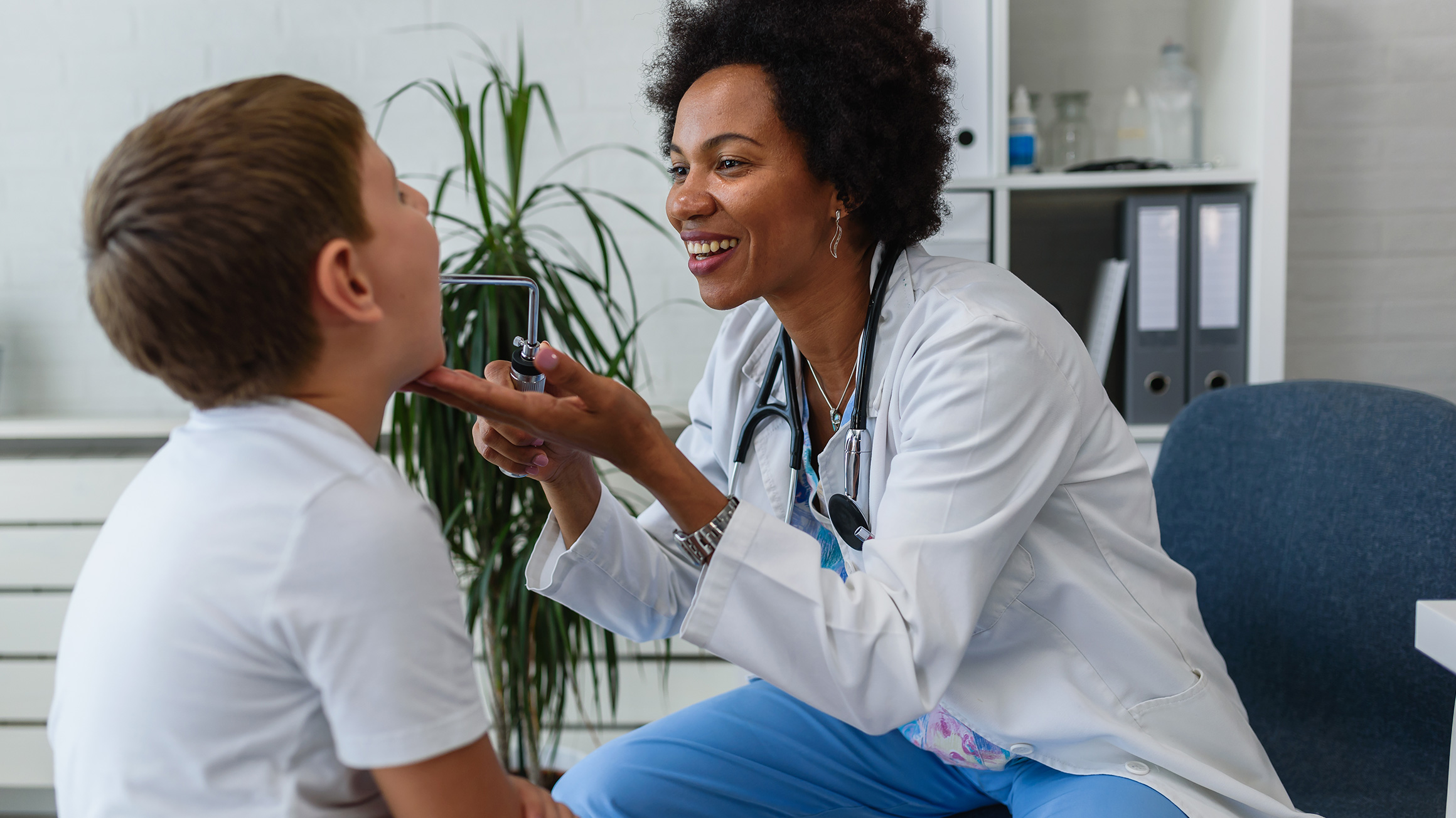 a nurse looks into a child patient's mouth in an office