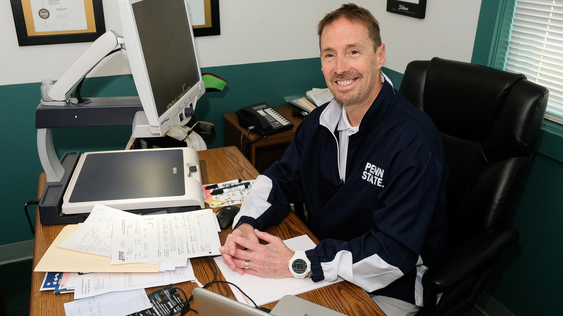 Monty Elam sits at a desk with a computer that enlarges text and reads text out loud.