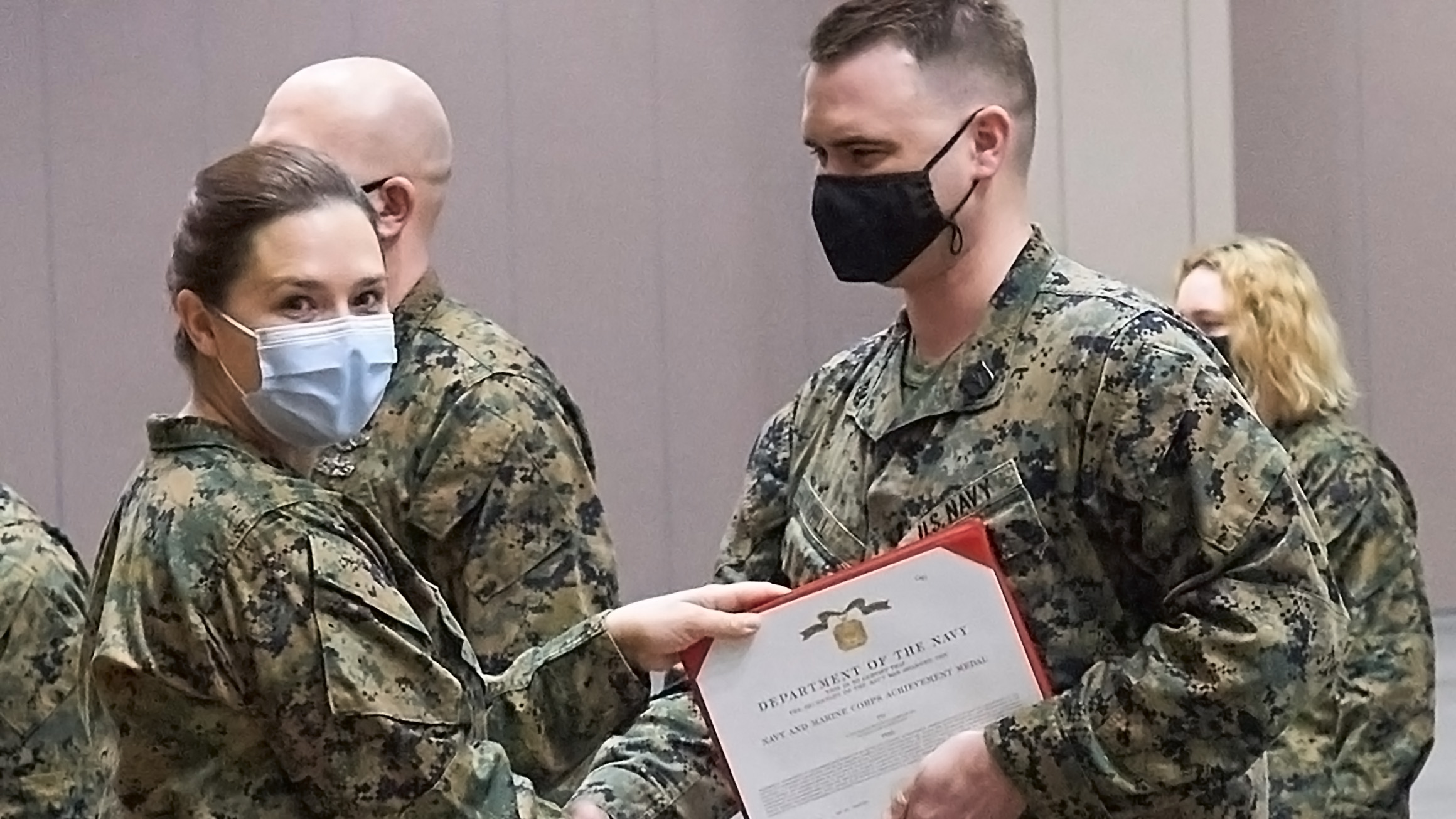 Bryan Hill is in camouflage and receives an award while wearing a mask