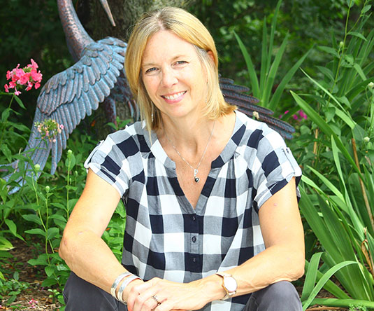 Janet Silbernagel Balster sits in a field