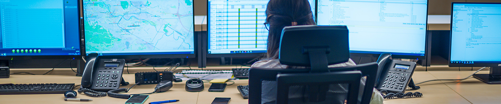 Decorative image of a woman monitoring multiple computer screens