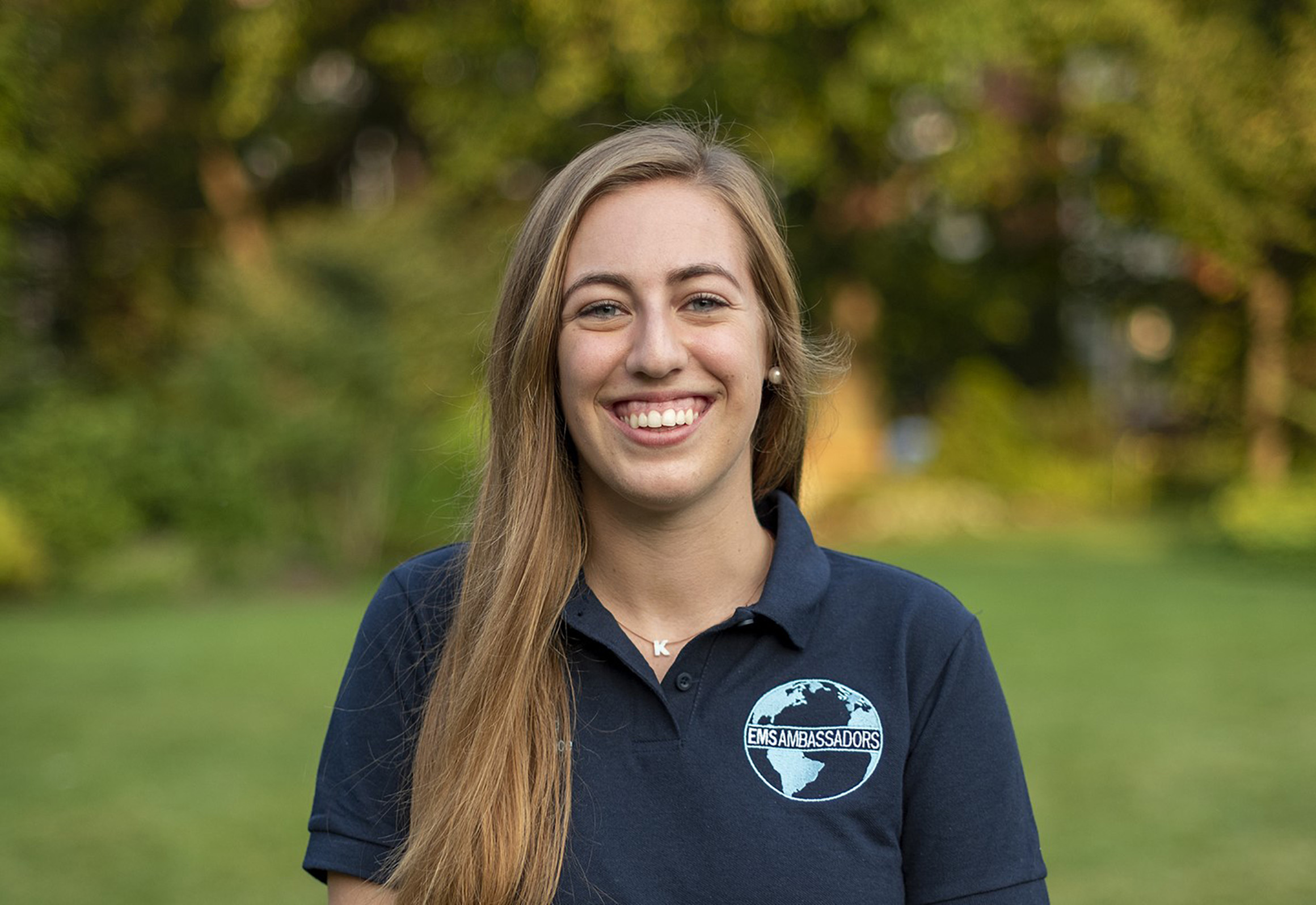 Karen Dedinsky stands in a field wearing a blue shirt