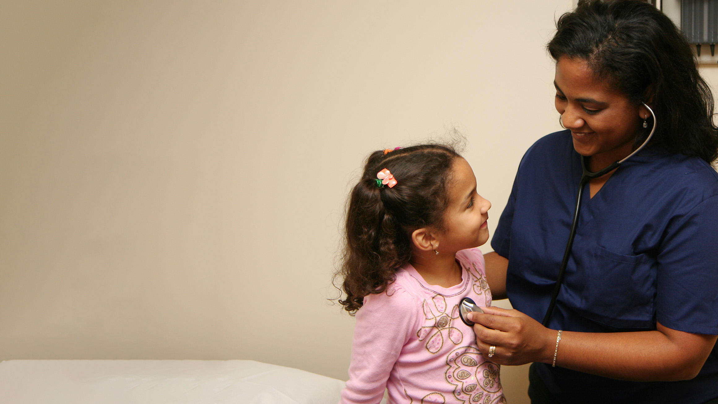 A nurse uses a stethoscope on a little girl