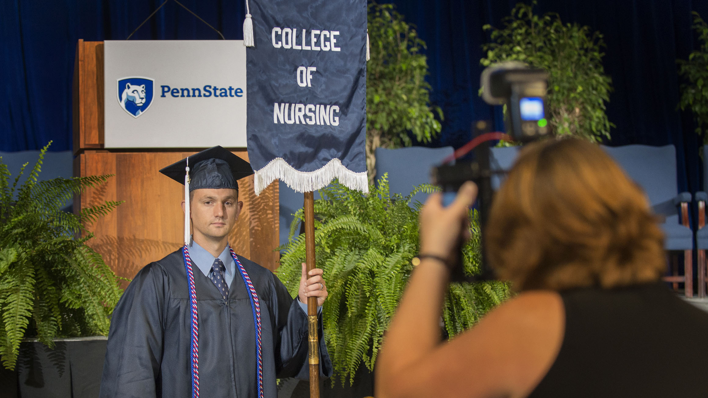 Brian Artiles holds a flag for the College of Nursing as its student marshal in 2017