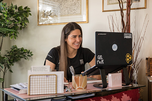 A woman sits at a desk working on a laptop.