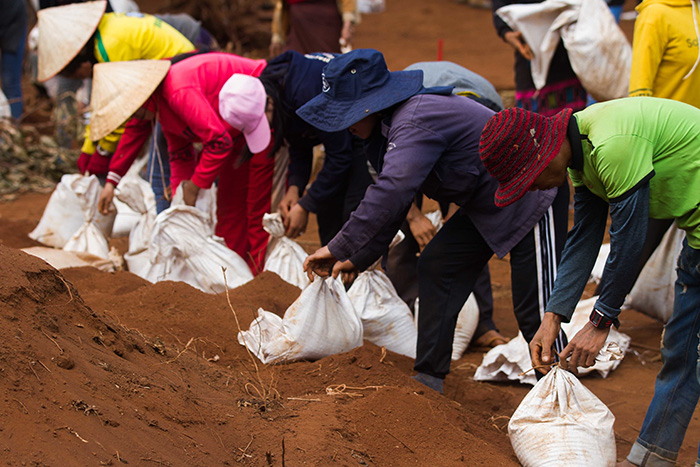 People stand in a line carrying bags of excavated soil.