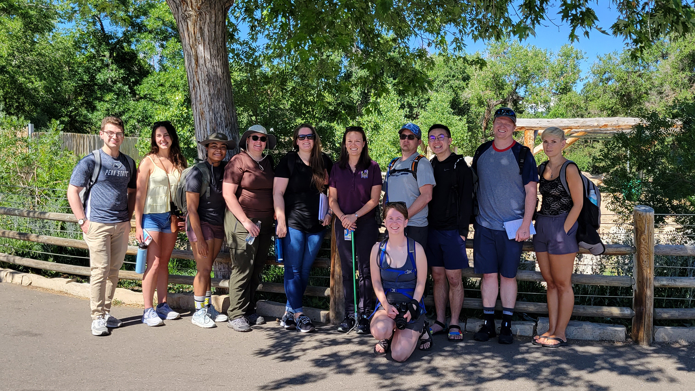 A group of people stand in a wooded area.