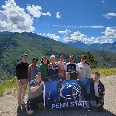 A group of people pose with a Penn State flag.