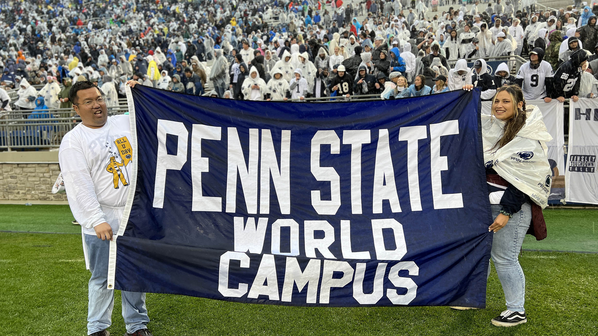 MacArthur Engstrand and Mattea Derr hold the Penn State World Campus banner on the field of Beaver Stadium.