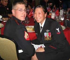 A man and a woman wearing military uniforms sit at a table.