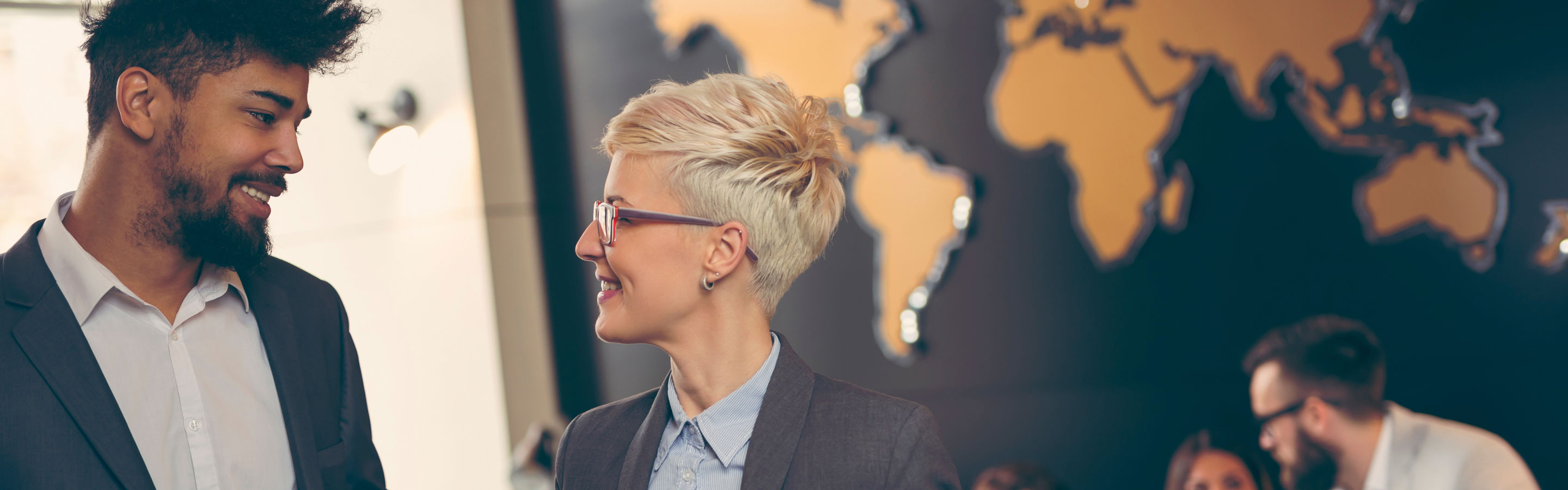 two professionals speaking in front of a world map 