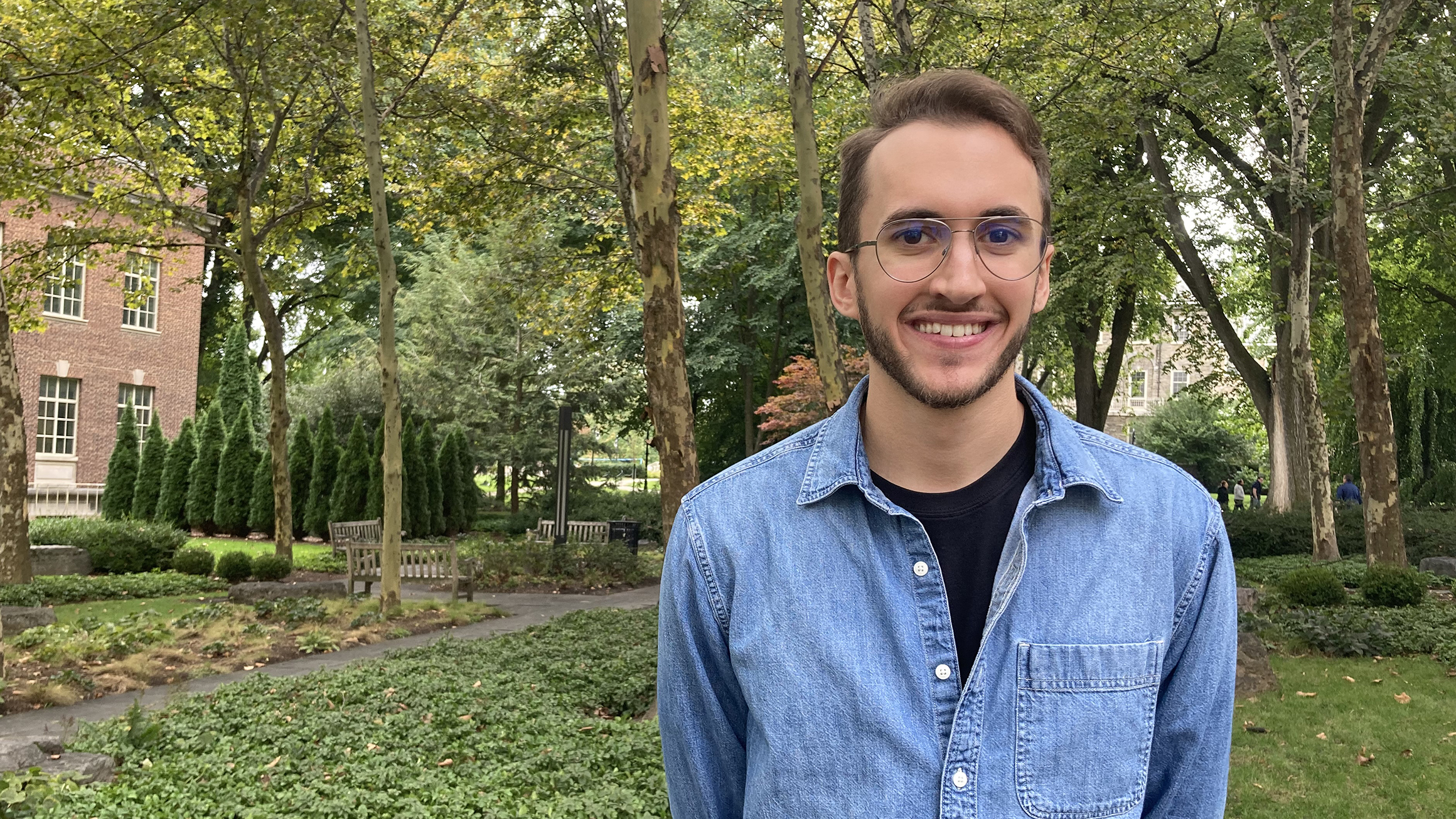 Daniel Serfass stands outside in a wooded courtyard.