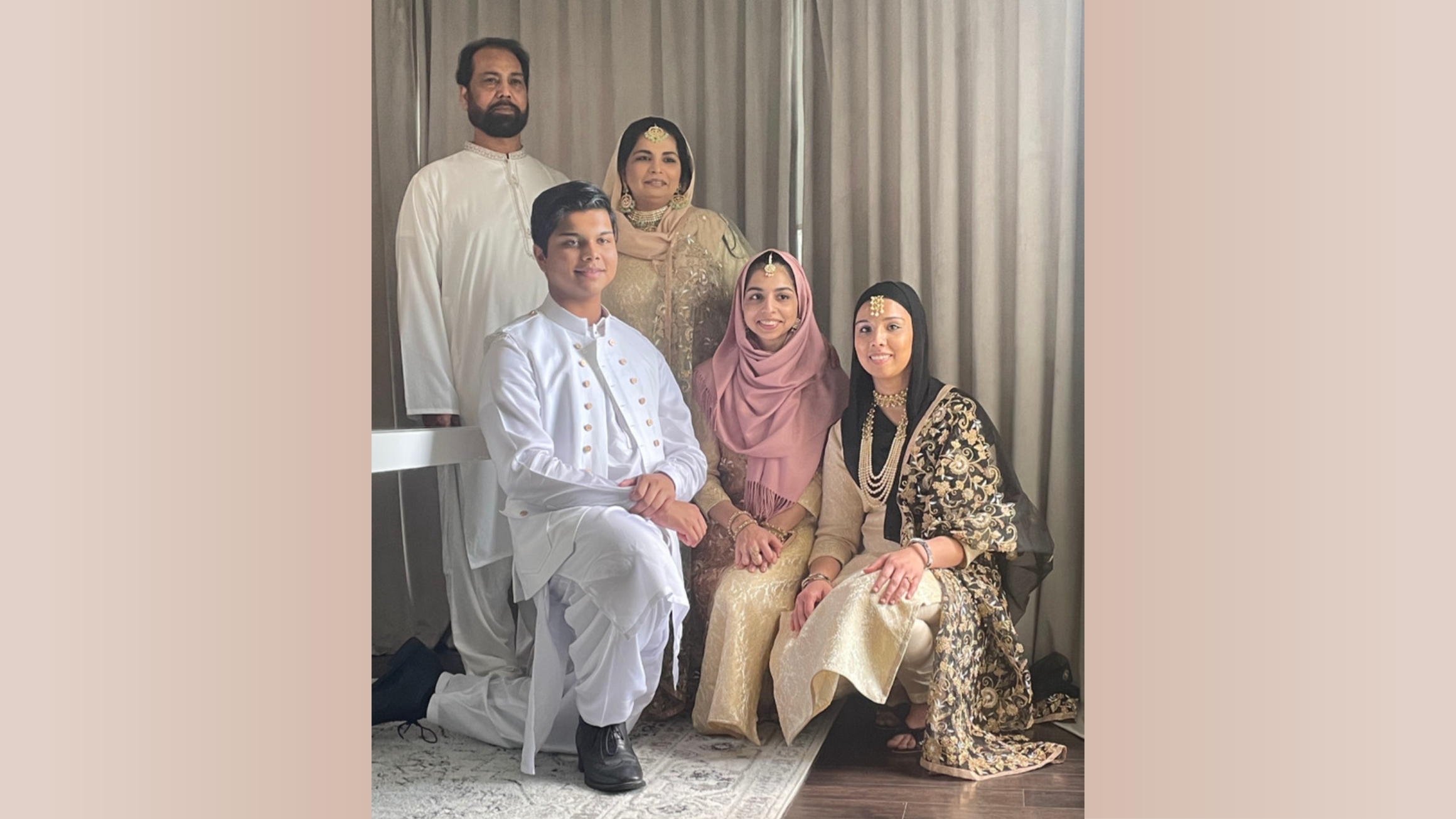 Five people pose for a photo in front of a tan curtain.