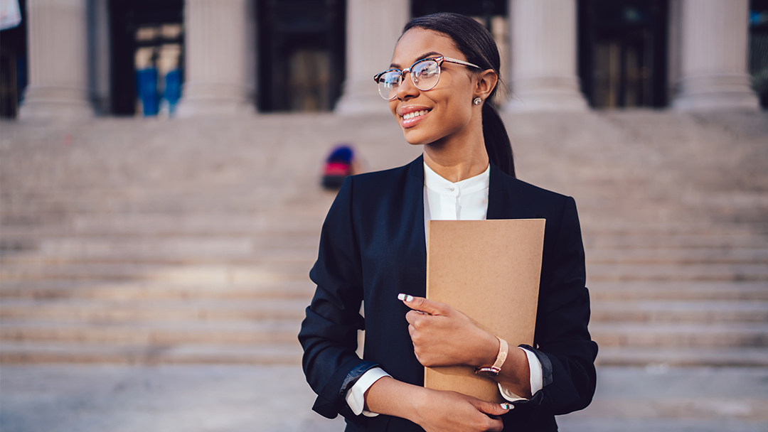 A woman in a suit holding documents outside of a court building