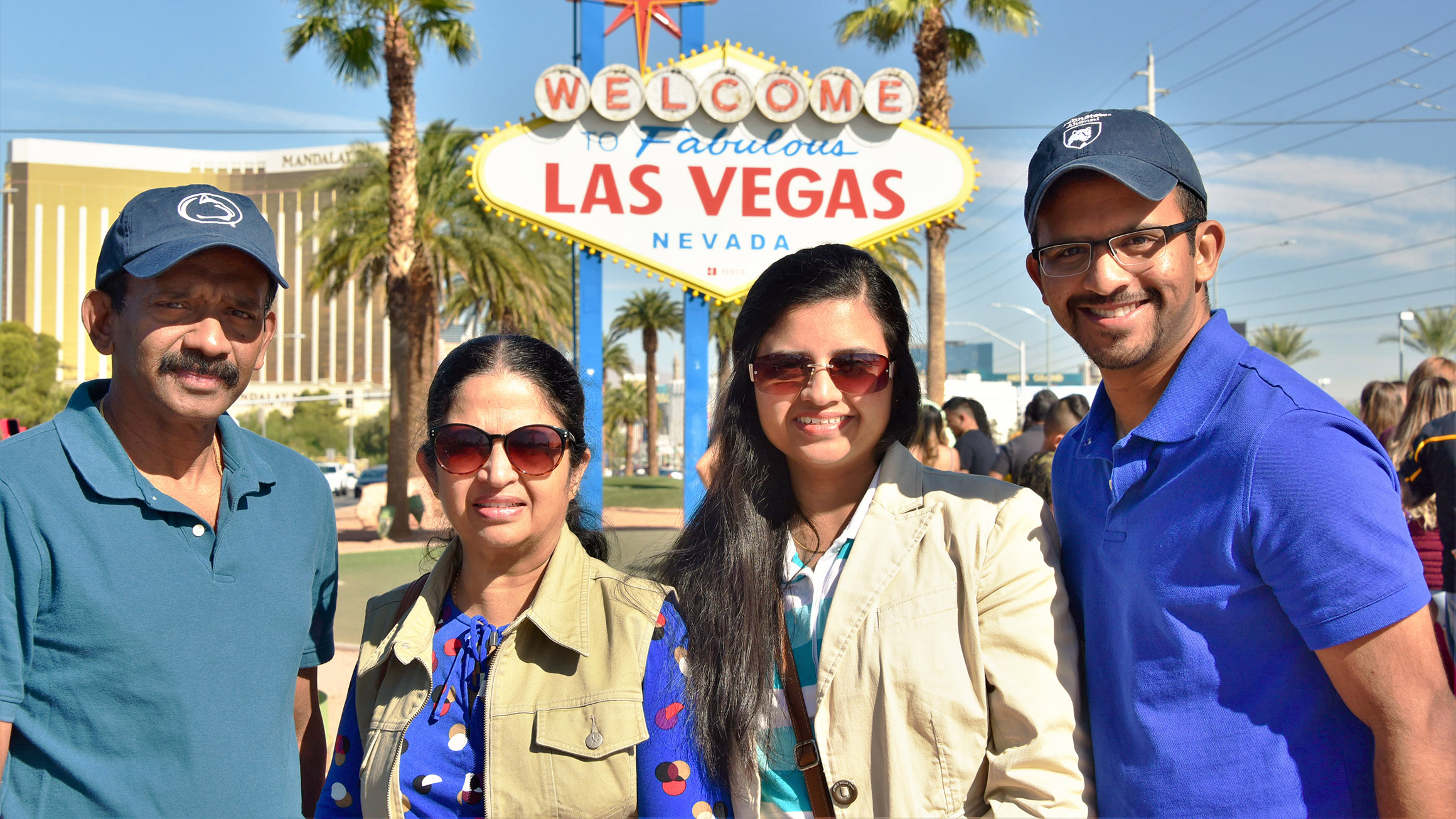Pavara Ranatunga stands with his mother, sister and father to the right him while while they pose with a Las Vegas sign in the background flanked by palm trees.