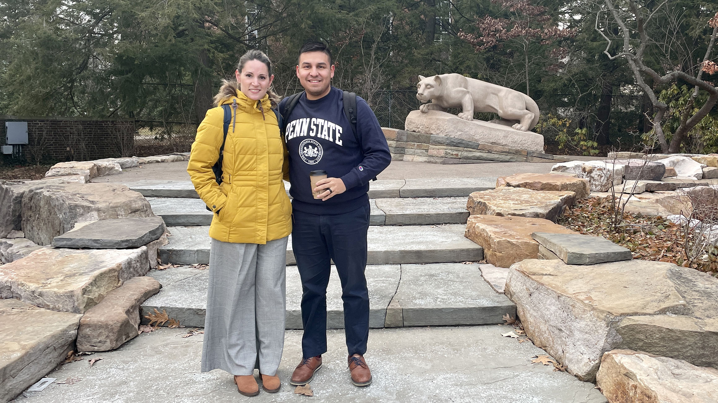 Marian Fuentes Viera and Sylvester Fernandez de Castro stand with the Nittany Lion shrine in the background.