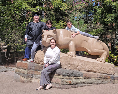 Four people pose at the Nittany Lion Shrine.