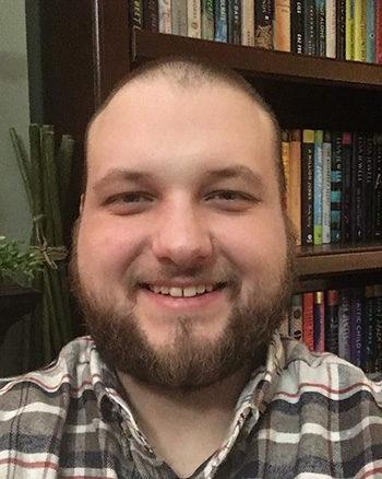 A photo of Ethan Donlan in front of a bookshelf.