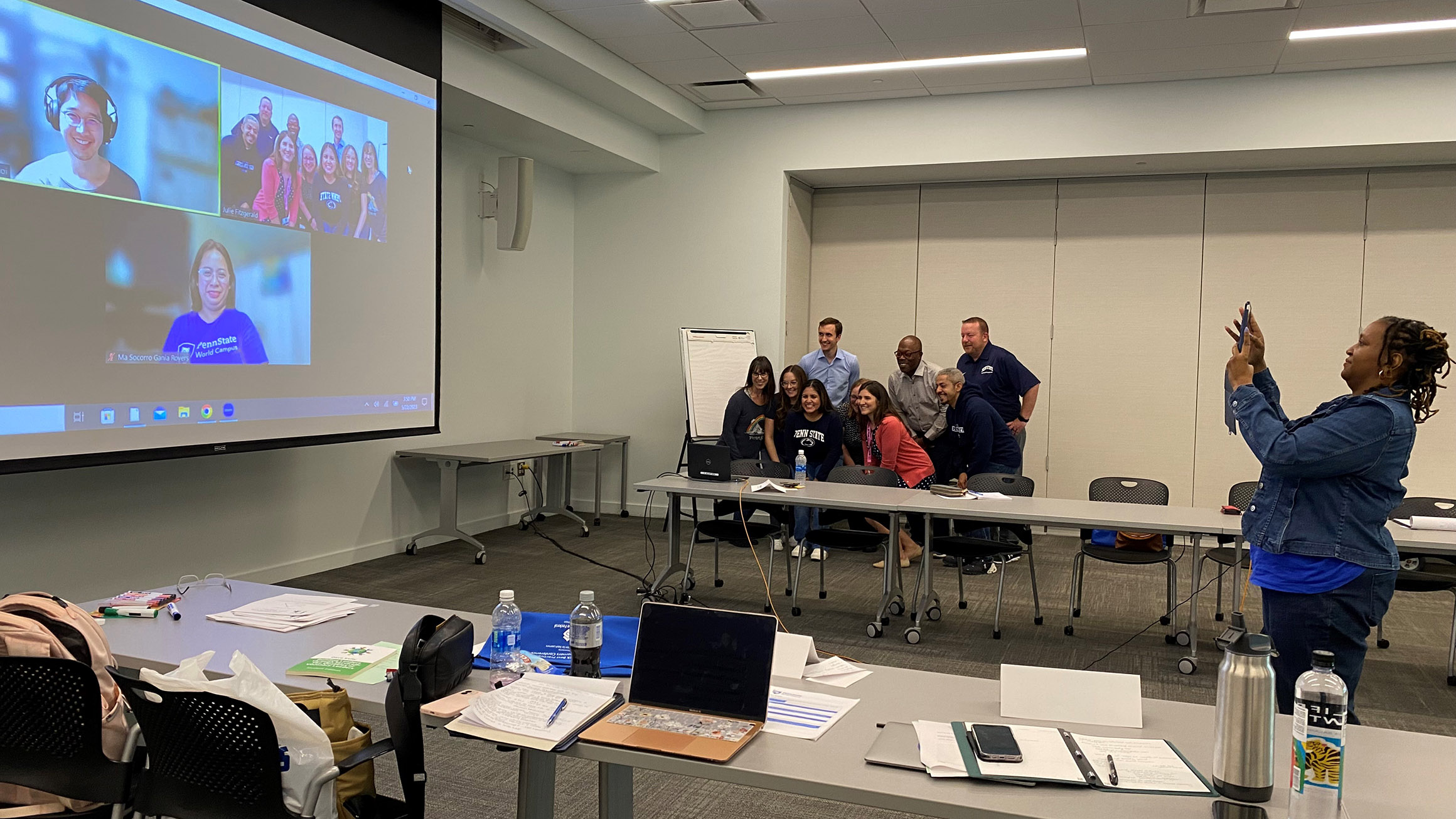 The attendees of the retreat posed for a photo by getting in front of the web cam of a laptop while someone takes a photo of the projection screen.