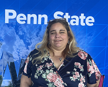 A woman stands in front of a Penn State-themed backdrop.