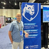 Man in polo shirt stands in front of Penn State World Campus banner.