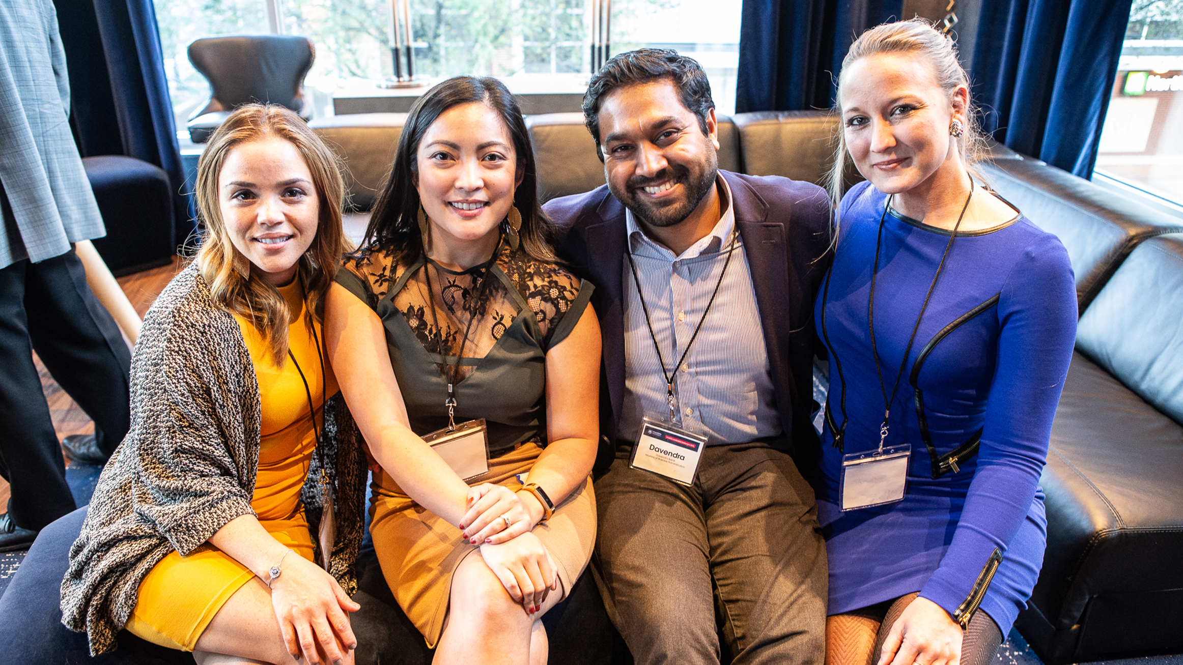 Four people sit on a couch.