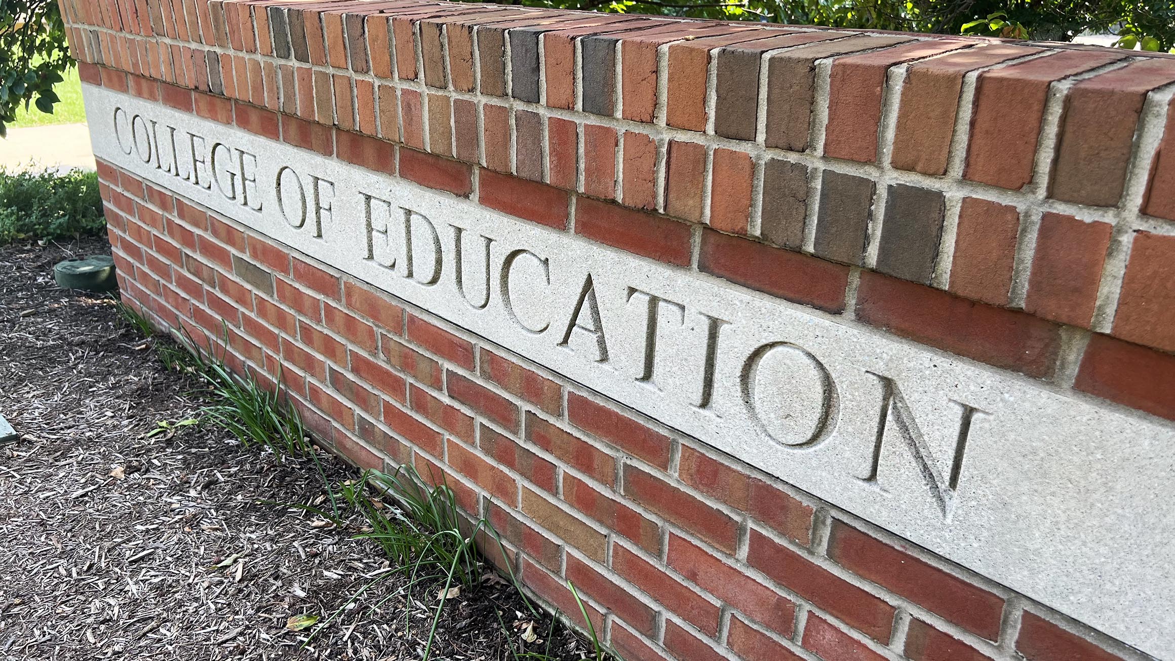 A brick wall has the words 'College of Education' on it