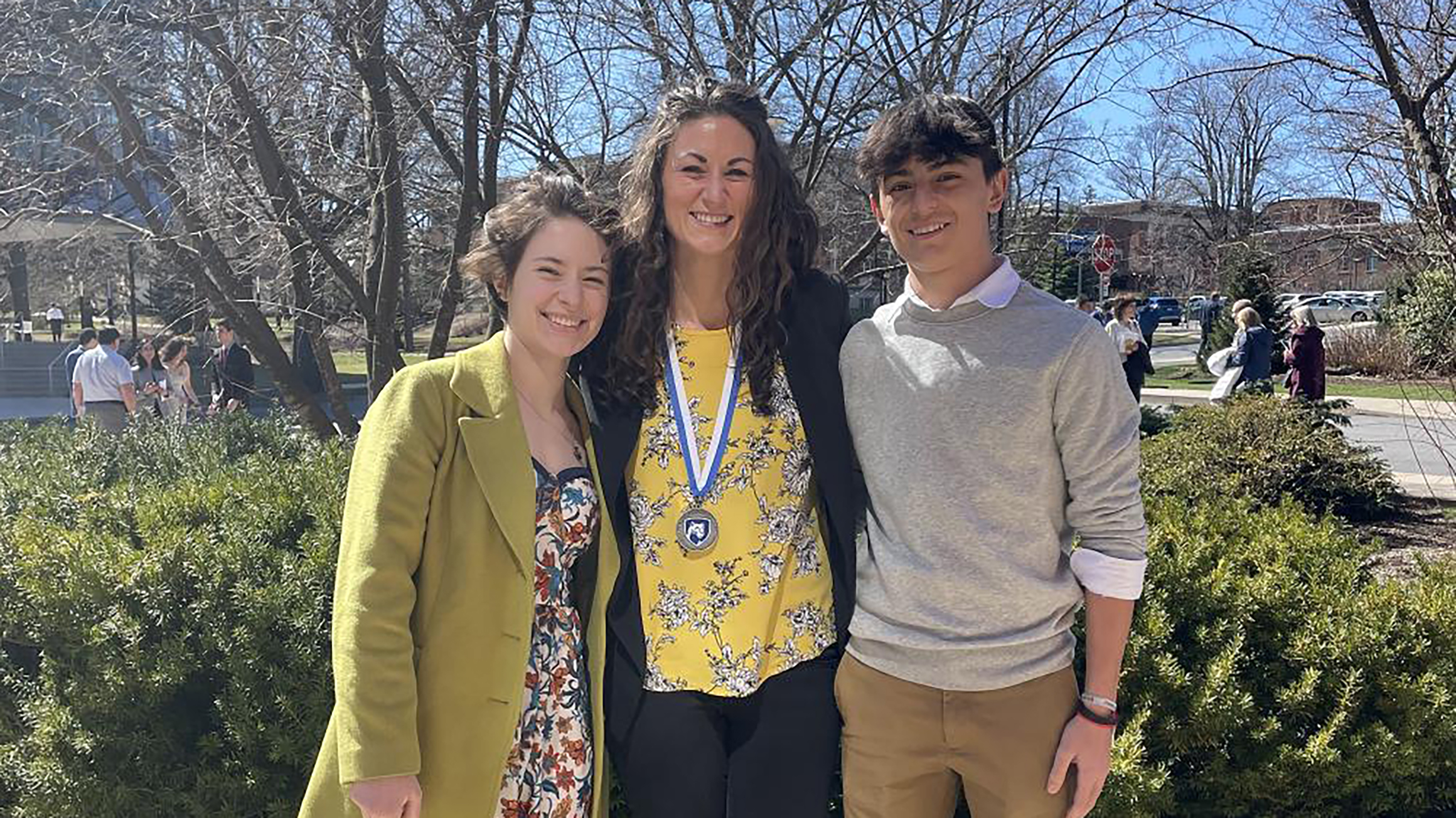 Three people pose for a photo outside.