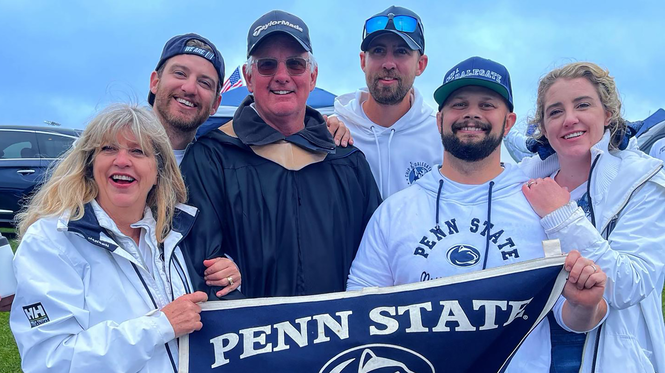 A group of people pose holding a Penn State banner.