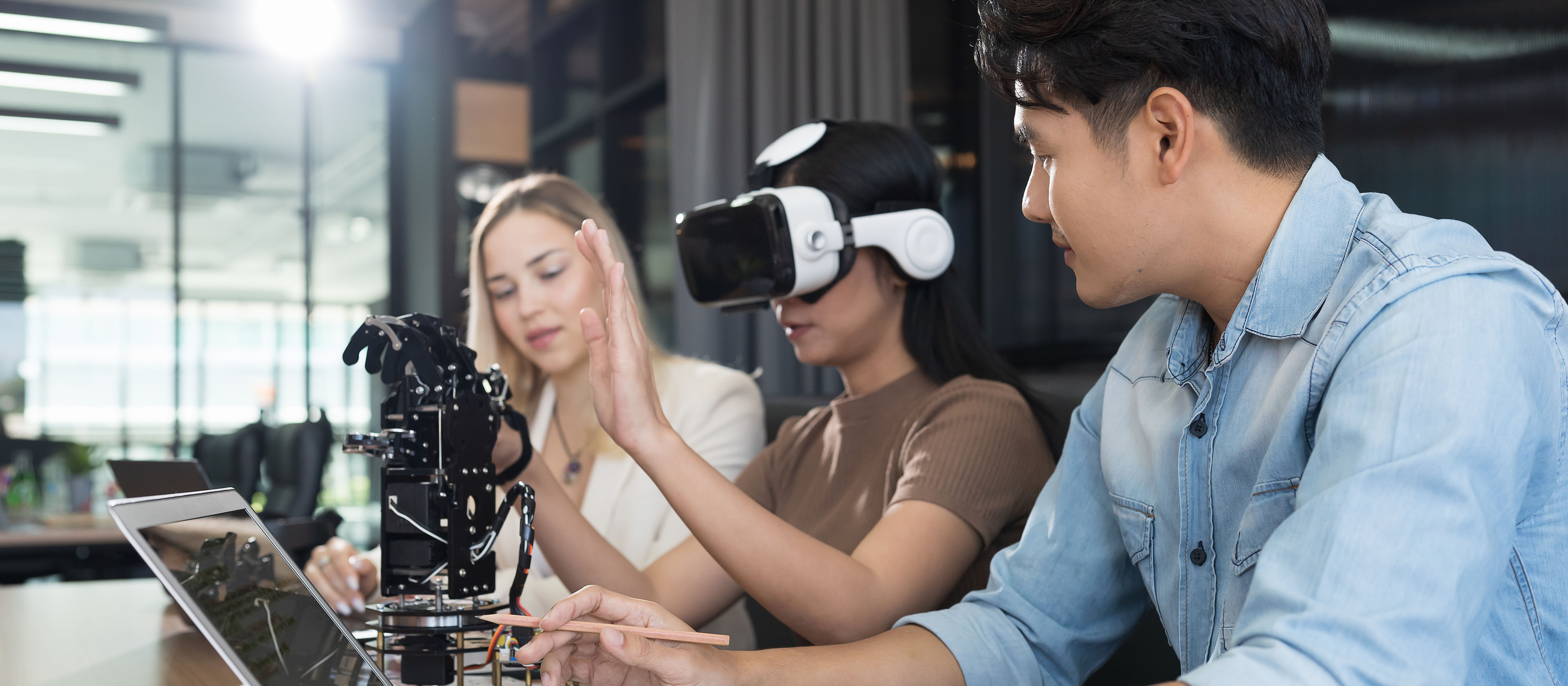 Woman wears virtual reality headset while two other people observe.