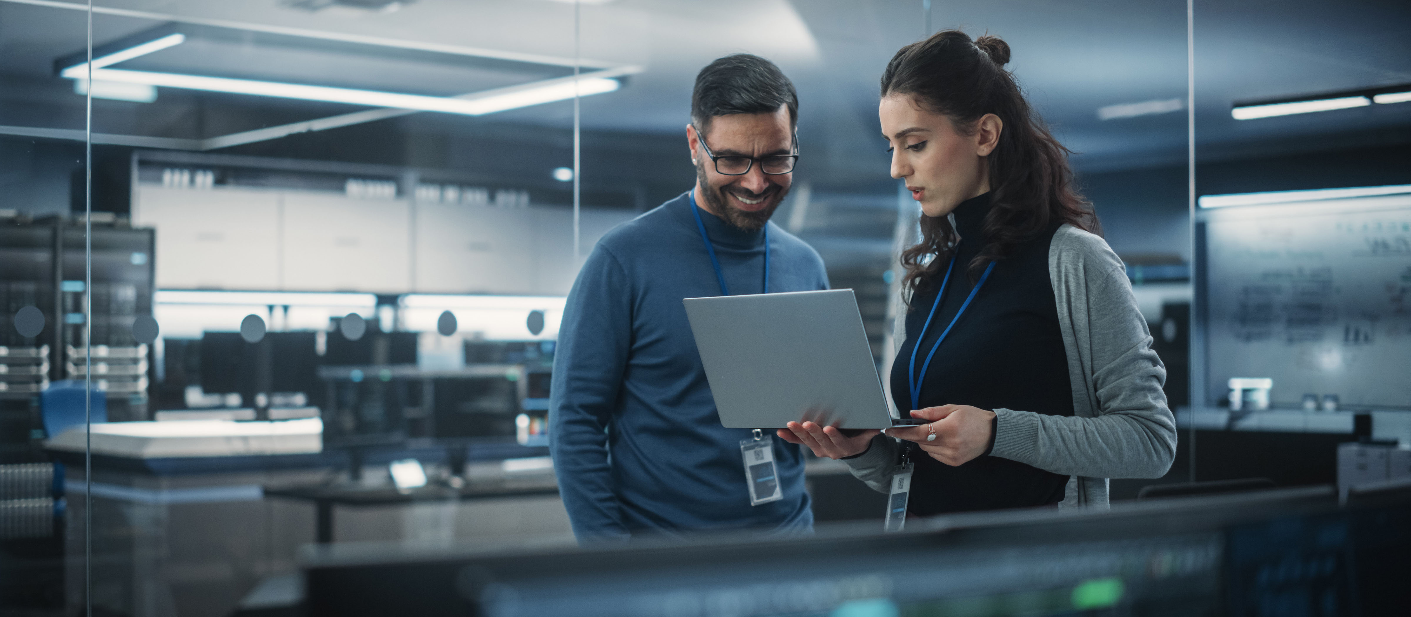 two data engineers looking at a laptop in an office setting