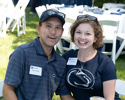Two people wearing Penn State gear sit at a table.