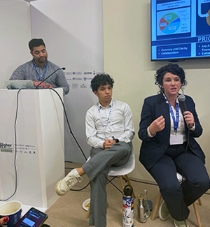 Olivia McMahon holds a microphone and presents her topic with two people beside her