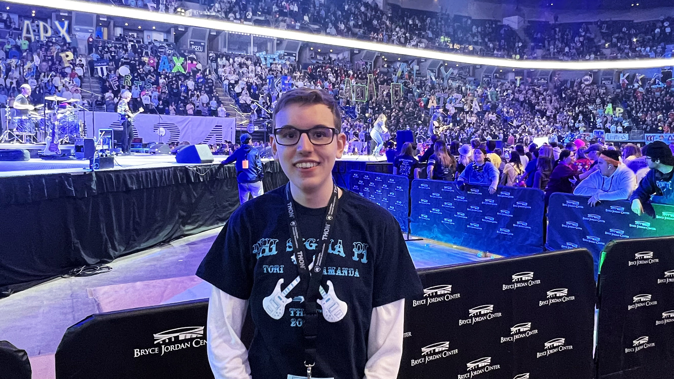 Braden Fleagle stands in front of a separator near a stage in a large arena